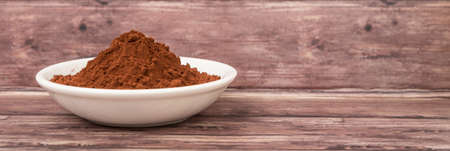 Cocoa powder in white bowl over wooden backgroundの写真素材