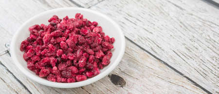 Dried pomegranate seeds in white bowl over wooden backgroundの写真素材