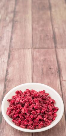 Dried pomegranate seeds in white bowl over wooden backgroundの写真素材
