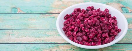 Dried pomegranate seeds in white bowl over wooden backgroundの写真素材