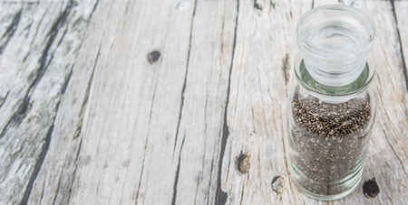 Black chia seeds in glass vial over wooden backgroundの写真素材