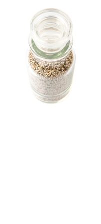 White chia seeds in glass vial over white background