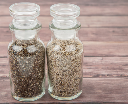 Black and white chia seeds in glass vial over wooden backgroundの写真素材