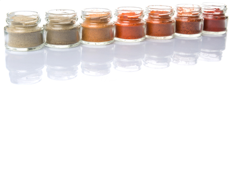 Hot and spicy spices powder, cayenne powder, chilly powder, peppercorn powder, paprika powder, black pepper and white pepper powder in small mason jar over white backgroundの写真素材