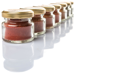 Hot and spicy spices powder, cayenne powder, chilly powder, peppercorn powder, paprika powder, black pepper and white pepper powder in small mason jar over white backgroundの写真素材