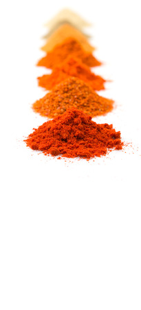 Pile of hot and spicy spices powder, cayenne powder, chilly powder, peppercorn powder, paprika powder, black pepper and white pepper powder over white backgroundの写真素材