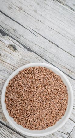 Flax seeds in white bowl over wooden backgroundの写真素材