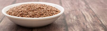 Flax seeds in white bowl over wooden backgroundの写真素材