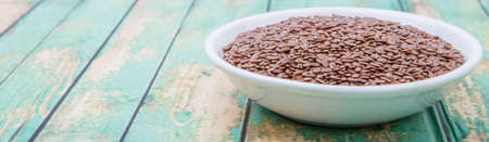 Flax seeds in white bowl over wooden backgroundの写真素材