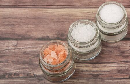 Table salt, sea salt and himalayan salt in mason jar over wooden background