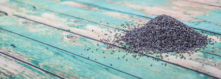 Black poppy seeds over wooden background