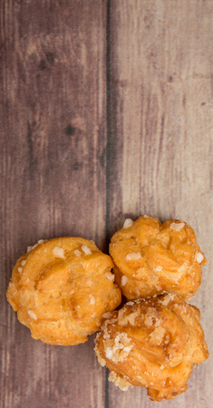 Choux pastry sprinkled with sugar over wooden background