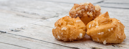 Choux pastry sprinkled with sugar over wooden background