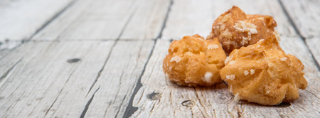 Choux pastry sprinkled with sugar over wooden backgroundの写真素材