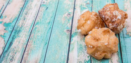 Choux pastry sprinkled with sugar over wooden background