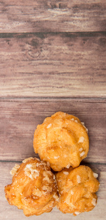 Choux pastry sprinkled with sugar over wooden background