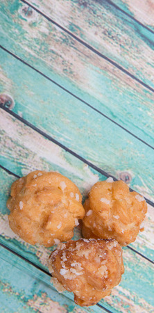 Choux pastry sprinkled with sugar over wooden background