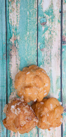Choux pastry sprinkled with sugar over wooden background