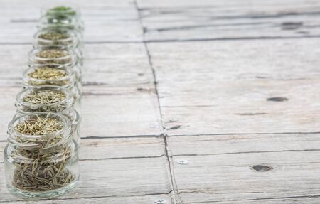 Dried parsley, estragon, marjoram, dill weed, thyme, rosemary and basil herbs in mason jar over wooden backgroundの写真素材