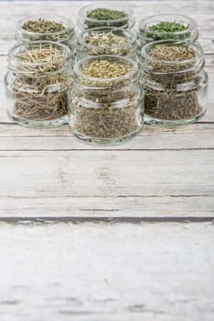 Dried parsley, estragon, marjoram, dill weed, thyme, rosemary and basil herbs in mason jar over wooden backgroundの写真素材