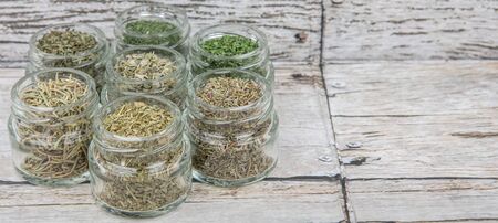 Dried parsley, estragon, marjoram, dill weed, thyme, rosemary and basil herbs in mason jar over wooden backgroundの写真素材
