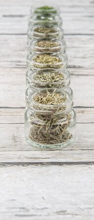 Dried parsley, estragon, marjoram, dill weed, thyme, rosemary and basil herbs in mason jar over...