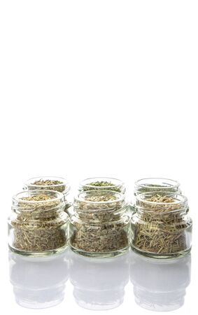 Dried parsley, estragon, marjoram, dill weed, thyme, rosemary and basil herbs in mason jar over white backgroundの写真素材