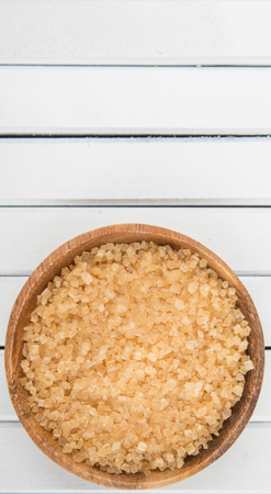 Brown sugar in wooden bowl over wooden backgroundの写真素材