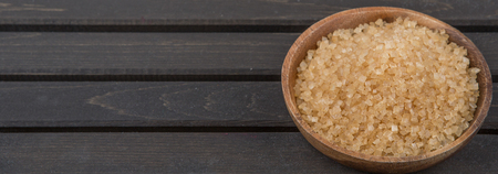 Brown sugar in wooden bowl over wooden backgroundの写真素材