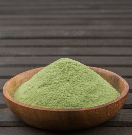 Green tea matcha powder in a bowl over wooden backgroundの写真素材
