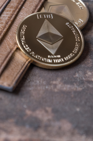 Ethereum coin in leather wallet over wooden background