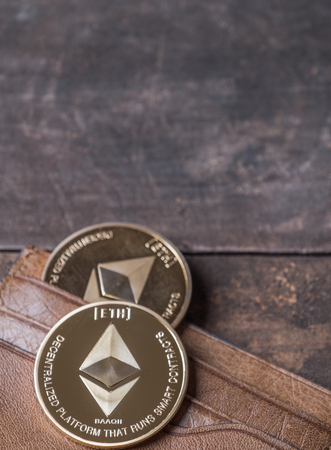 Ethereum coin in leather wallet over wooden backgroundの写真素材