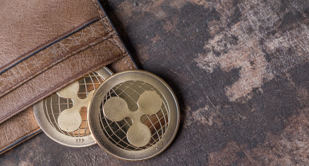 Ripple coin in leather wallet over wooden background