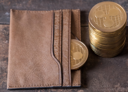 Ripple coin with lether wallet on wooden table top