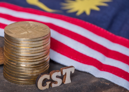 'GST' words with golden coins and Malaysian flag background