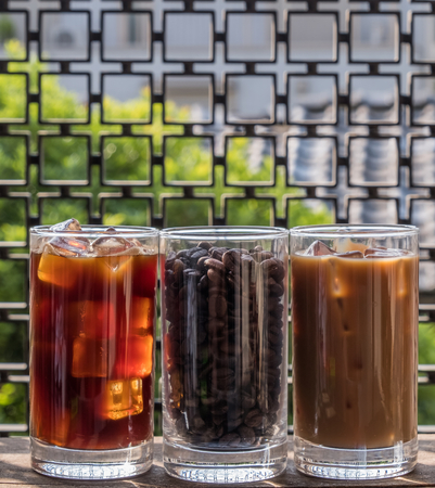 Black iced coffee, milk coffee, and beans over wooden backgroundの写真素材