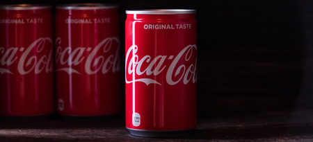 TOKYO, JAPAN - JUNE 17TH, 2018. Coca cola drinks on wooden table top with dark background