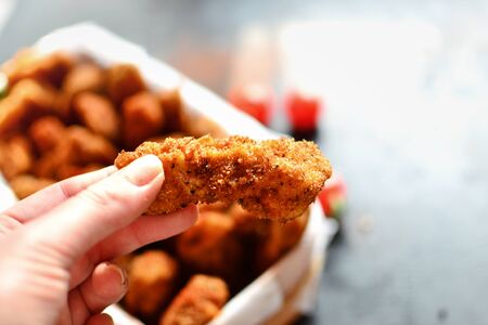 Chicken nuggets on a dark background. Grilled fish and meat in batter. Fish sticks. Meat sticks. Nuggets with tomato and parsley in a basket. Free Place for your text.の写真素材