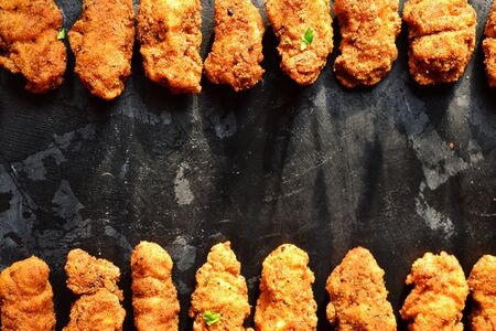 Fried crispy chicken nuggets on a dark background. Tasty fried chicken meat isolated. Place for text. Top viewの写真素材