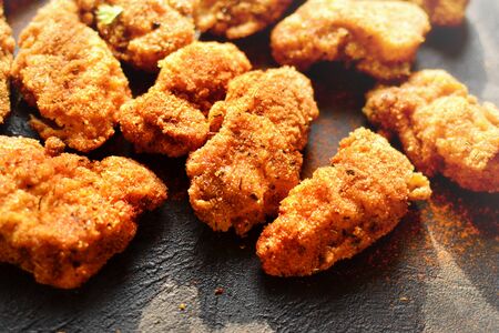 Fried crispy chicken nuggets on a dark background. Tasty fried chicken meat isolated. Place for text.の写真素材