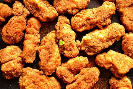 Fried crispy chicken nuggets on a dark background. Tasty fried chicken meat isolated. Place for text. Top viewの写真素材