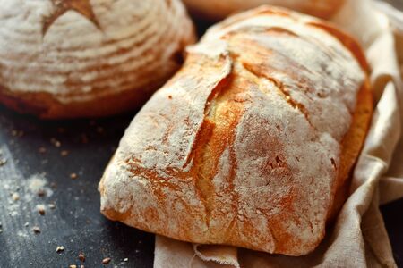 Bakery products in a wicker basket. Round homemade bread, long loaf with seeds, vegan bread without...