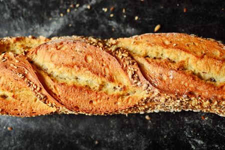 Bakery products. Crispy, beautiful bread on a dark background. Buckwheat, without yeast, wheat bread with flax and sunflower seeds. Top view, place for text.の写真素材