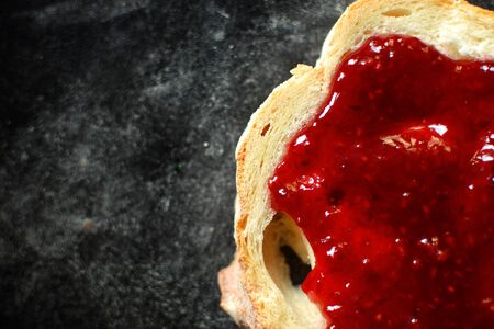 Sandwich with raspberry jam. Sandwich on a dark background isolated. Delicious raspberry and...