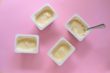 The food is minimal in style. Minimal food concept. Yogurt in a cup. Yogurt on a pink pastel background. Top view. A free place for text. Healthy breakfast and snack foods.の写真素材