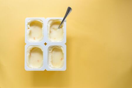 The food is minimal in style. Minimal food concept. Yogurt in a cup. Yogurt on a yellow pastel background. Top view. A free place for text. Healthy breakfast and snack foods.の写真素材