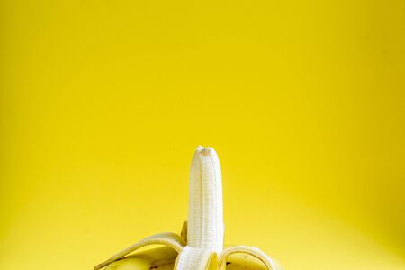Minimal food concept. Bananas on a bright yellow background. Free space for text. Minimalism. Creative fruits.の写真素材