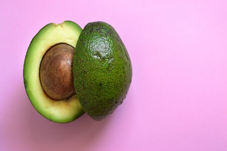 Cut avocado. Avocado on a pastel pink background. Free space for text. Top view. Flat lay....