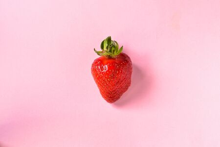 Minimal food concept. Strawberries on a pink background. One strawberry isolated. Top view. Free space for text. Tasty berries.の写真素材