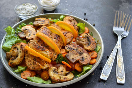 Grilled vegetables and chicken breast salad. Chicken breast, salad, mushrooms, tomatoes, orange. Dark backgroundの写真素材